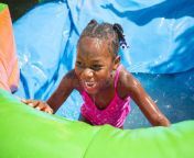 smiling little girl playing outdoors inflatable bounce house water slide cute african american having fun 65562392.jpg from daughter slip
