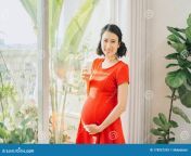 young asian pregnant woman holding milk glass standing behind window young asian pregnant woman holding milk glass 178957293.jpg from sex preagnant milk asian tits drink black