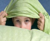 boy peeking out of his duvet from kids sleeping naked