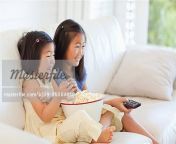 6109 06004848em side view of two sisters watching tv and eating popcorn while sitting.jpg from two sister premium show on tango