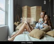 front view of sweet happy young couple sitting and hugging on bed at home young stylish brunette girl lying and relaxing in arms of smiling boyfriend in glasses concept of love relationship 2ambf5j.jpg from couple romance in kissing with sex