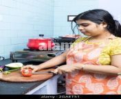 a pretty indian young woman wearing apron cooking and cutting vegetables in domestic kitchen on gas stove 2gaet51.jpg from desi aunty in kitchen