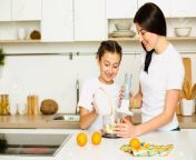 93512457 daughter helps mom prepare breakfast mixing fruit in a blender standing at white kitchen family.jpg from helps mom