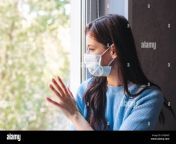 young woman in quarantine wearing a protective mask and looking through the window 2crjh6d.jpg from wear mask quarantine