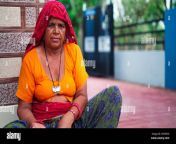 portrait of indian senior woman sitting near main entrance and looking at camera 2r93fkd.jpg from old aunty outdoor
